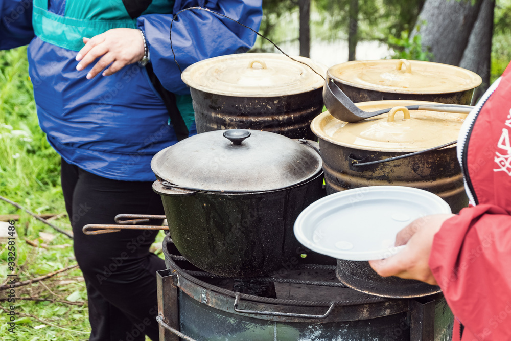 Fototapeta premium Charity outdoor food. A hungry man with a plate in his hand is waiting for food.