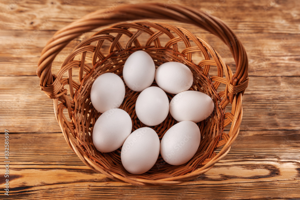 A few white eggs in a basket on a wooden table. The view from the top. A few white eggs in a basket on a wooden table. The view from the top.