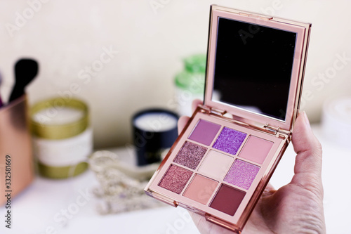 Makeup eyeshadow palette in female hand on the white background.