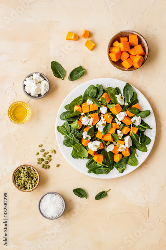 Salad with pumpkin and basil - near ingredients - on beige background top-down