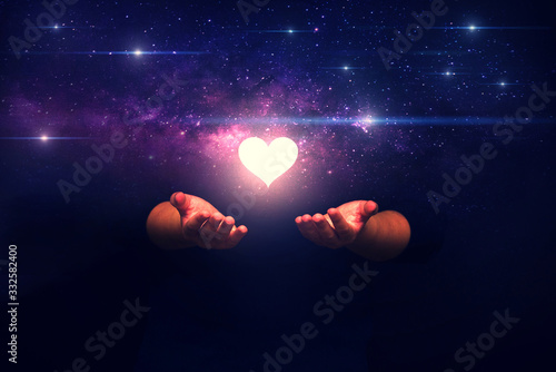 Spiritual image: hands with shining heart shape and spaceship ,Love from universe and love from gods concept. photo