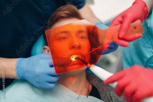 Dentistry. Dentist and patient. Light curing seal. UV dental lamp and orange protect glass. Dental fillings.