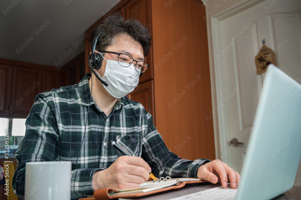 An Asian man who is self-isolated and working from home because of a massive pandemic. An Asian man who is self-isolated and working from home because of a massive pandemic.