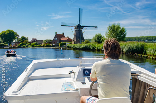 Tableau sur toile Family vacation, summer holiday travel on barge boat in canal, man by steering w