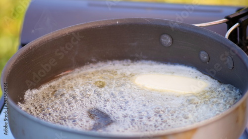 Pieces of butter melting in hot oil pan.