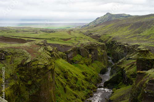 Beautiful river with tiny waterfall in Iceland surrounded by green cliff