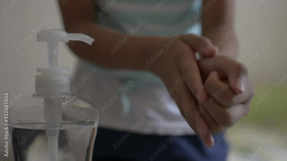 Asian cute girl cleaning her hands with alcohol gel and wearing protective mask in bedroom during COVID-19 outbreak situation. Coronavirus protection. Asian cute girl cleaning her hands with alcohol gel and wearing protective mask in bedroom during COVID-19 outbreak situation. Coronavirus protection.