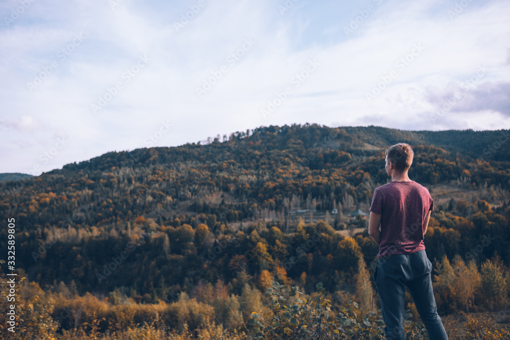 man looking at autumn forest mountains