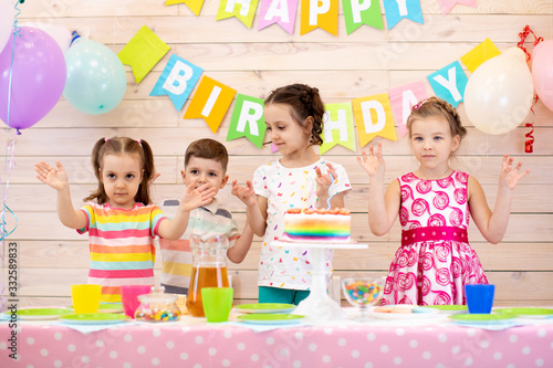 Children celebrating birthday party. Happy kids stand at festive table