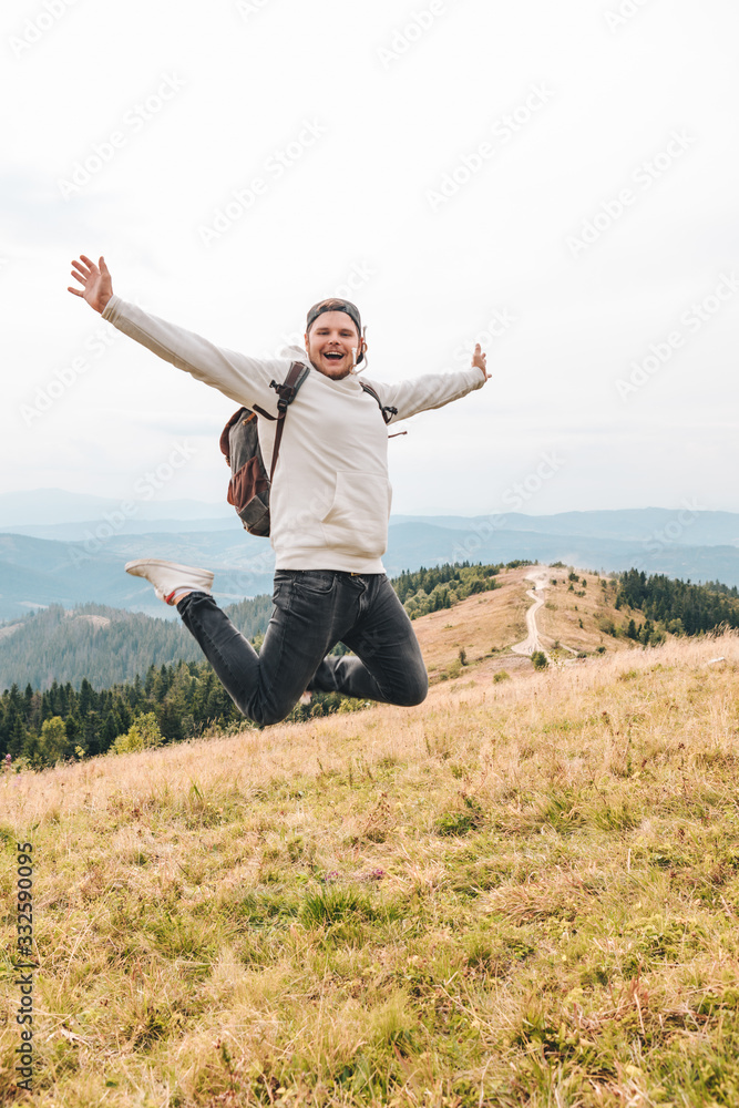 man with backpack happy jumping on the peak on the mount man with backpack happy jumping on the peak on the mount