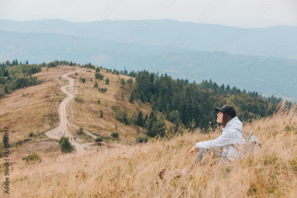 woman sitting on the ground looking at mountains hiking concept