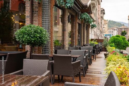 Empty terrace with tables and chairs in wood and metal at coffee and resteurant beside sidewalk in center city. Background business dramatic scene concept. Stay home concept