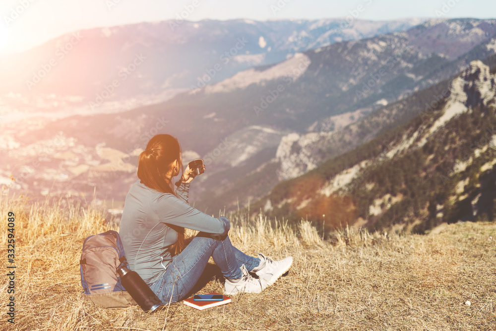 Young beautiful girl travels alone in the mountains in spring or autumn ...