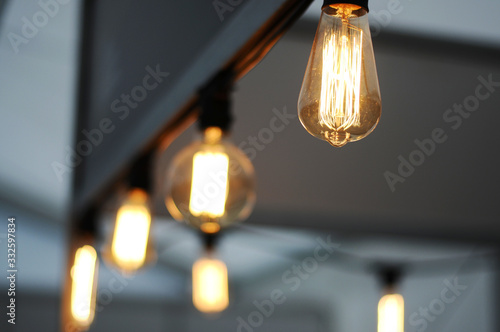 Incandescent lamps in a modern cafe, blurred background, Edison Lamp, lamps for interior and design, yellow filament lamps in a cafe, close-up. © Олександр Цимбалюк