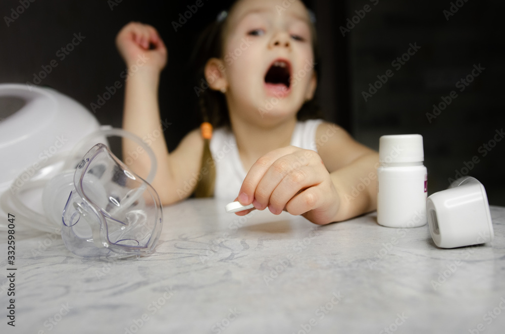 Naklejka premium A child sits with an inhaler at home. Coronovirus treatment concept Covid19. Girl making inhalation with nebulizer at home. child asthma inhaler inhalation nebulizer steam sick cough