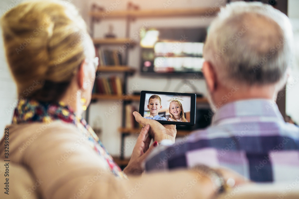 Senior couple making video call on digital tablet with their grandchildren.Quarantine. Health concept. - obrazy, fototapety, plakaty 