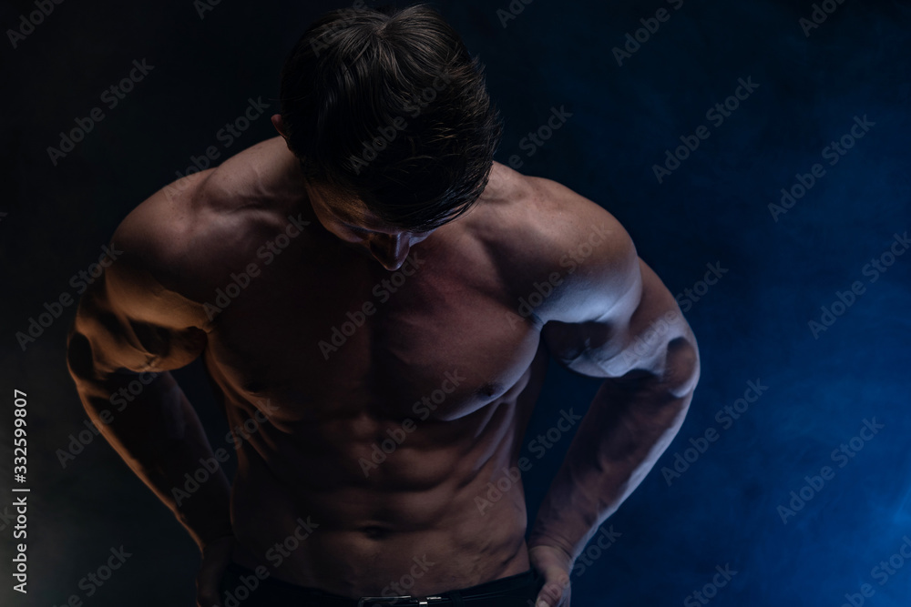 Fototapeta premium Muscular man showing muscles isolated on the black background with colored smoke. Concept of healthy lifestyle 