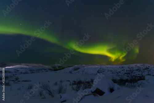 Aurora and stars in the sky .The rocks and ground are covered with snow.Arctic. © Moroshka