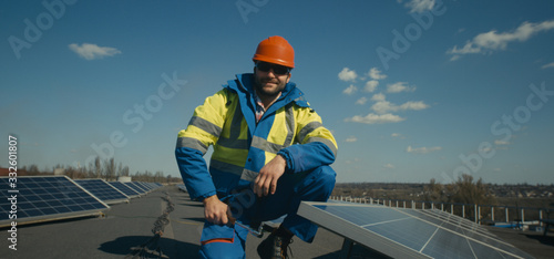 Technician installing solar panel and looking at camera