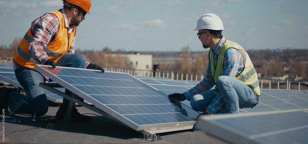 Technicians installing solar panels on metal stand