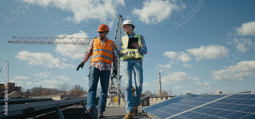 Engineer and technician discussing between solar panels