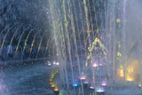 Splashes of a fountain illuminated by colored lights in the town square