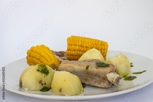 Fototapeta Naklejka Na Ścianę i Meble -  Potatoes, pineapples and ribs, a typical dish from the island of Tenerife. The potatoes, pineapples and ribs are accompanied by a green mojo. The green mojo is coriander. Tipical from canary islands.
