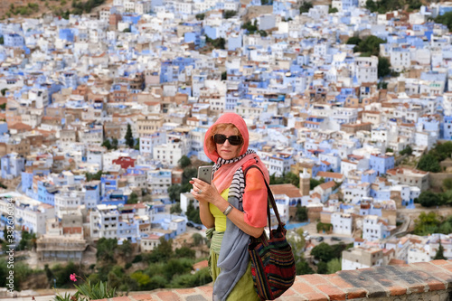 Lonely middle-aged woman in a traditional shawl overlooks the Chefchaouen city in Morocco.