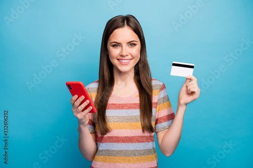 Close-up portrait of her she nice lovely pretty charming confident cheerful cheery girl holding in hand device plastic card buy online isolated over bright vivid shine vibrant blue color background