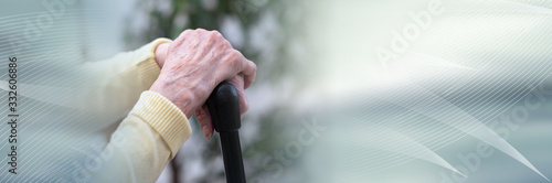 Old woman hands holding a cane; panoramic banner