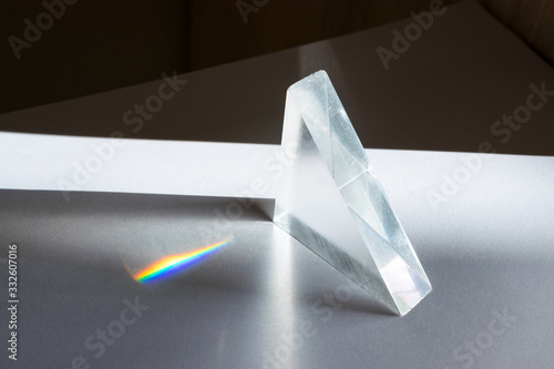Sunlight passes through a prism, causing the light to refract and spread, creating a spectrum of colors