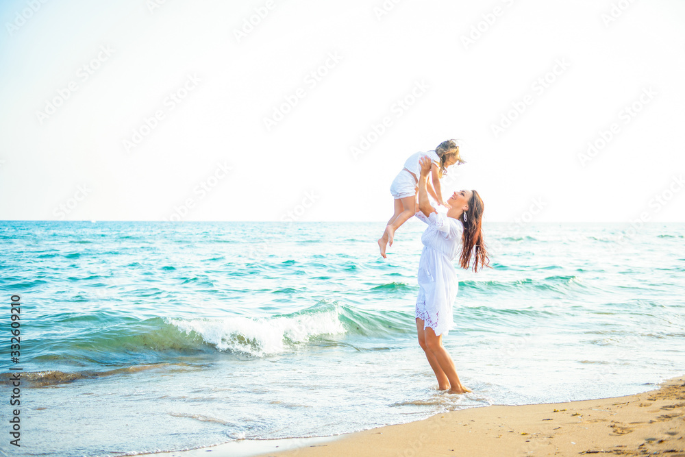 Happy family mom and little daughter play and fool around the coast on sea beach at resort Happy family mom and little daughter play and fool around the coast on sea beach at resort
