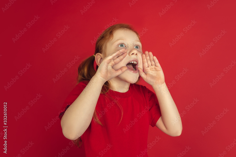 Calling, shouting. Caucasian little girl portrait isolated on red studio background. Cute redhair model in red shirt. Concept of human emotions, facial expression, sales, ad, childhood. Copyspace. Calling, shouting. Caucasian little girl portrait isolated on red studio background. Cute redhair model in red shirt. Concept of human emotions, facial expression, sales, ad, childhood. Copyspace.