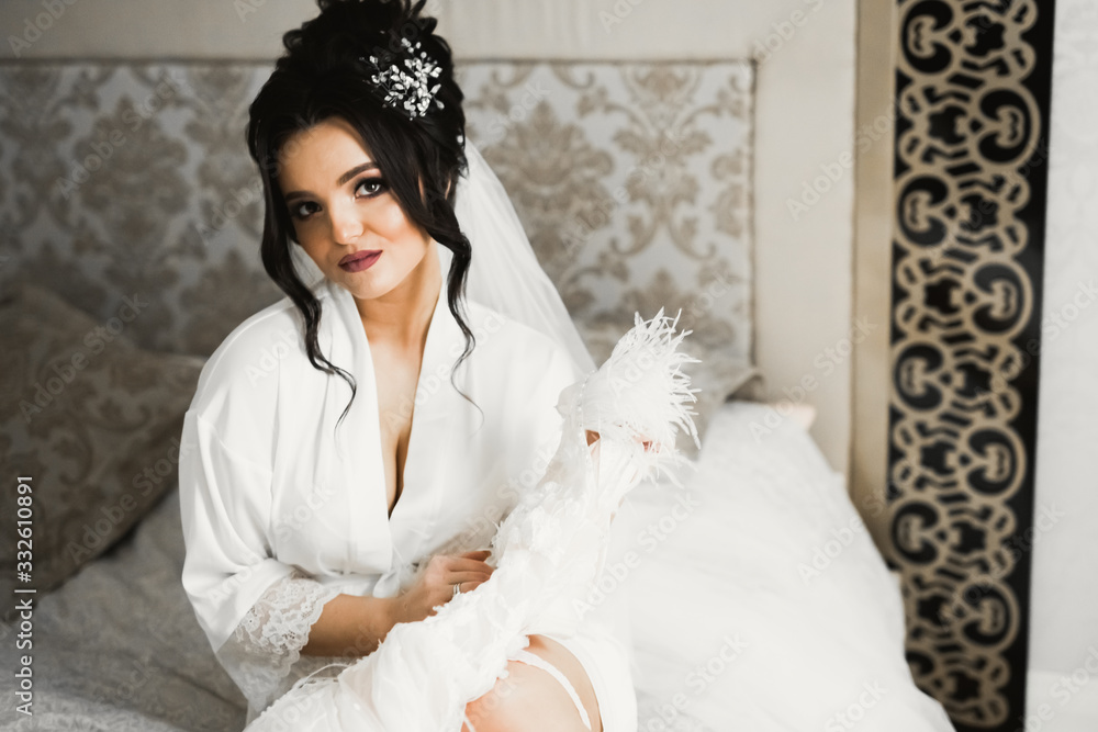 Gorgeous bride in robe posing and preparing for the wedding ceremony face in a room Gorgeous bride in robe posing and preparing for the wedding ceremony face in a room