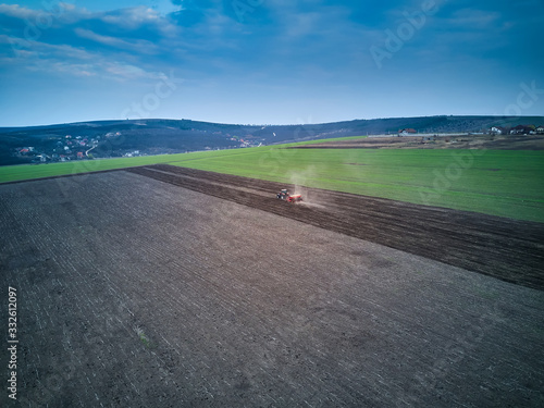 Tractor in a field performing spring sowing., top view from drone pov photo