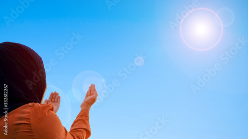 beautiful asians muslim women praying to god for thank on blue sky and sunlight background, add lens flare.