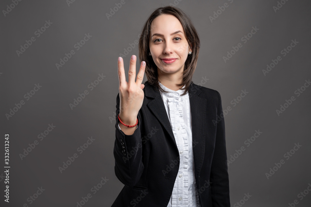 Portrait of wonderful young business woman counting three with her finger, poseing on isolated gray background Portrait of wonderful young business woman counting three with her finger, poseing on isolated gray background