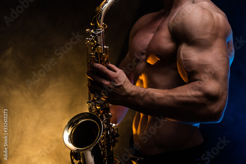 Wallpaper Mural Muscular man with naked torso playing on saxophone with smoked colorful backgrou
