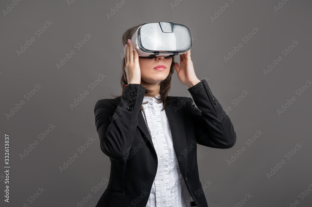 Portrait of wonderful young business woman wearing virtual reality VR glasses, poseing on isolated gray background Portrait of wonderful young business woman wearing virtual reality VR glasses, poseing on isolated gray background