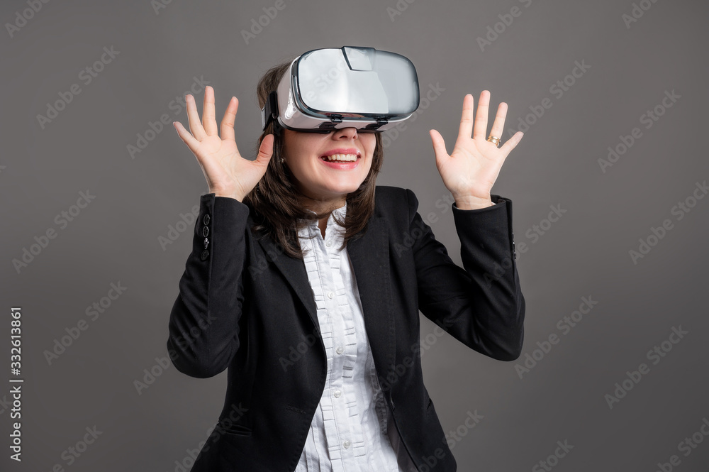 Portrait of wonderful young business woman wearing virtual reality VR glasses, poseing on isolated gray background Portrait of wonderful young business woman wearing virtual reality VR glasses, poseing on isolated gray background