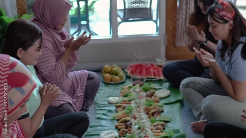 kembulan. woman friends smiling looking at camera while having lunch together. asian javanese traditional eating together sitting on floor photo