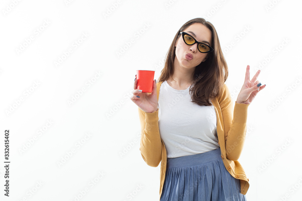 Brunette in a yellow sweater drinks coffee from a red cup Brunette in a yellow sweater drinks coffee from a red cup