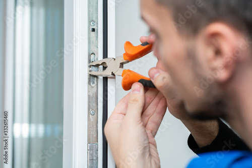 Professional master for repair and installation of windows, sets up a window opening system in winter mode