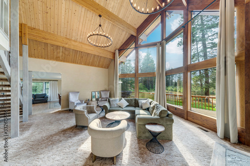 Amazing living room with three story tall vaulted wooden ceiling, huge windows, two large round chandeliers, venetian plaster, open staircase, beautiful design.