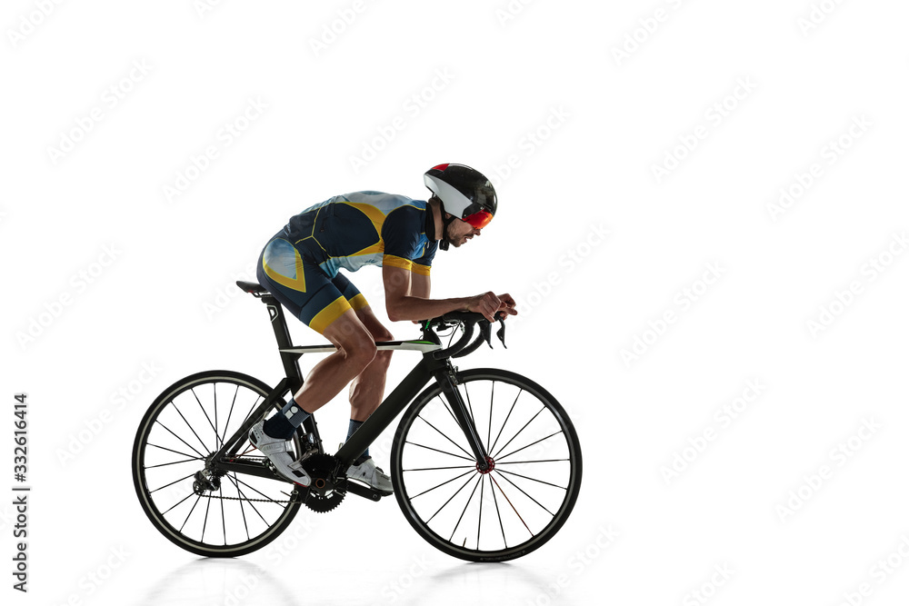 Fototapeta premium Triathlon male athlete cycle training isolated on white studio background. Caucasian fit triathlete practicing in cycling wearing sports equipment. Concept of healthy lifestyle, sport, action, motion.