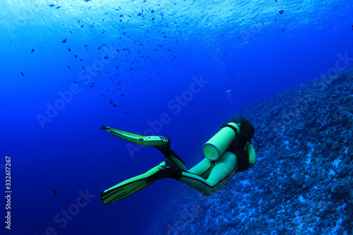 Female scuba diver explores beautiful coral reef