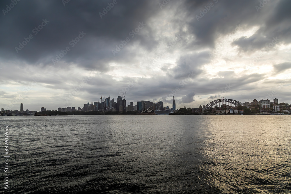 Sydney in Australia, the skyline with the Opera house and the Harbour Bridge during a cloudy but warm day.