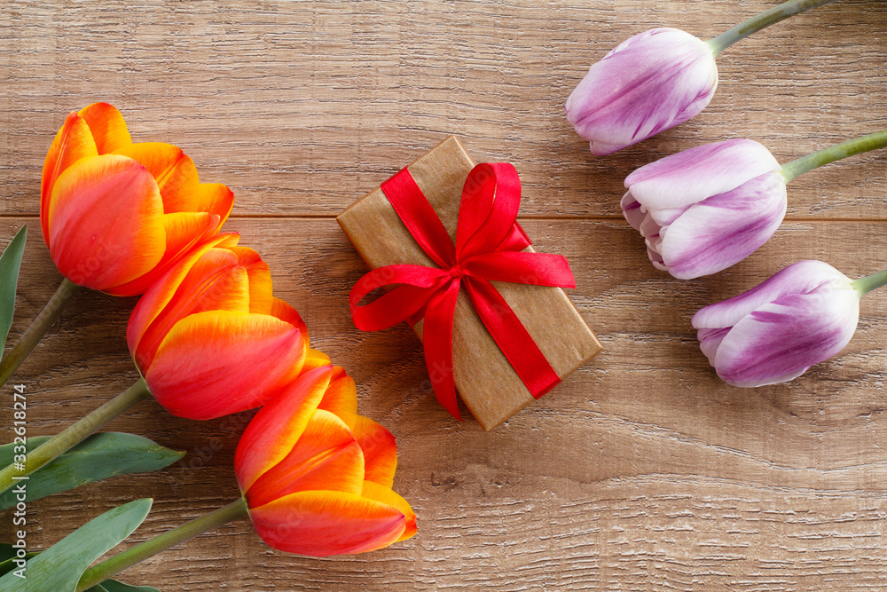 Gift box with red ribbons and tulips on wooden boards. Gift box with red ribbons and tulips on wooden boards.