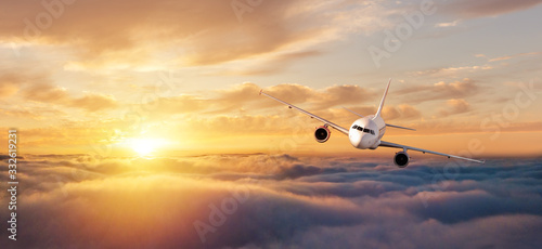 Commercial airplane flying over dramatic sunset