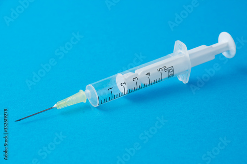 Close-up of transparent plastic syringe on blue background horizontally with copy space